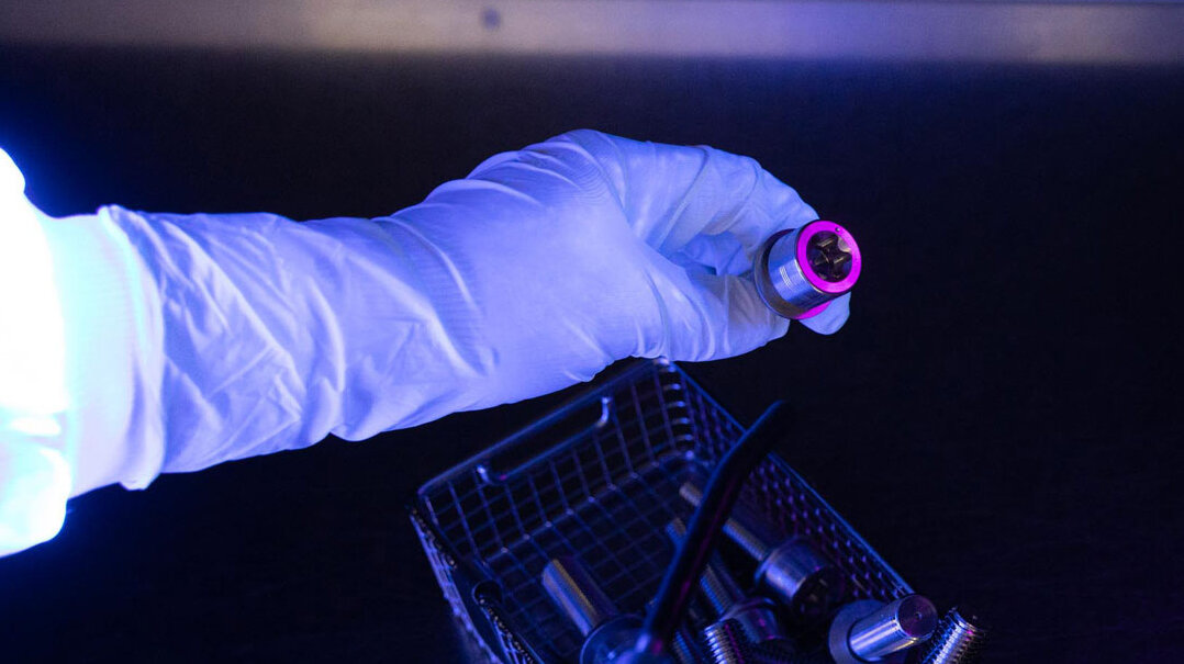 An employee uses a black light to check whether there is any contamination on one of the products