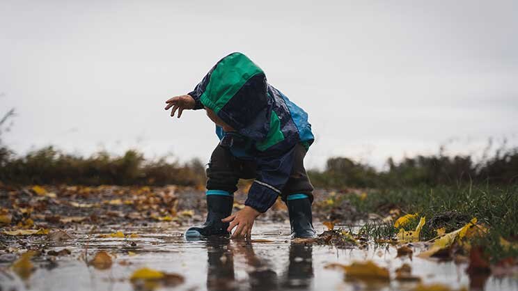Ein Kind spielt im Regen