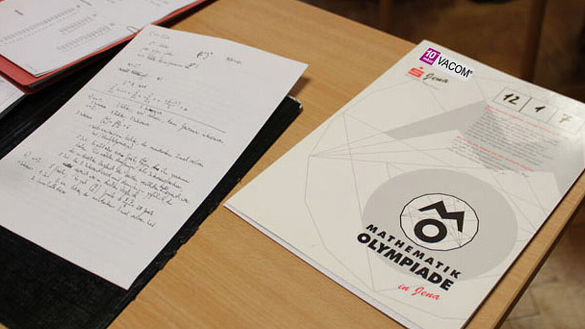 Auf einem Tisch liegen verschiedene Unterlagen für eine Mathematik-Olympiade