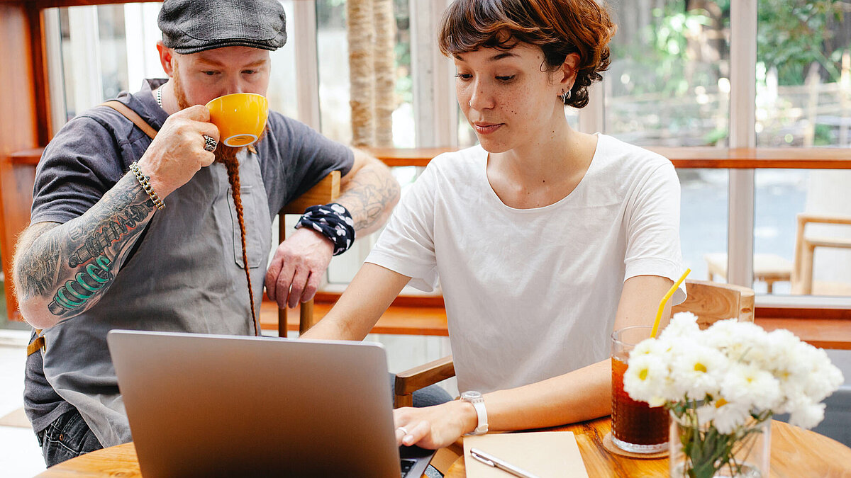 https://www.pexels.com/photo/young-woman-using-laptop-while-man-in-cap-drinking-coffee-6205758/