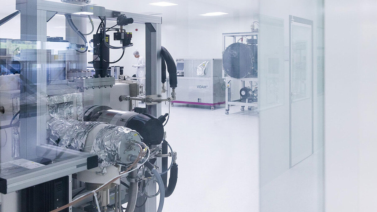 Ultrafinecleaning; Employee walks past the VIDAM cleaning oven in the clean room